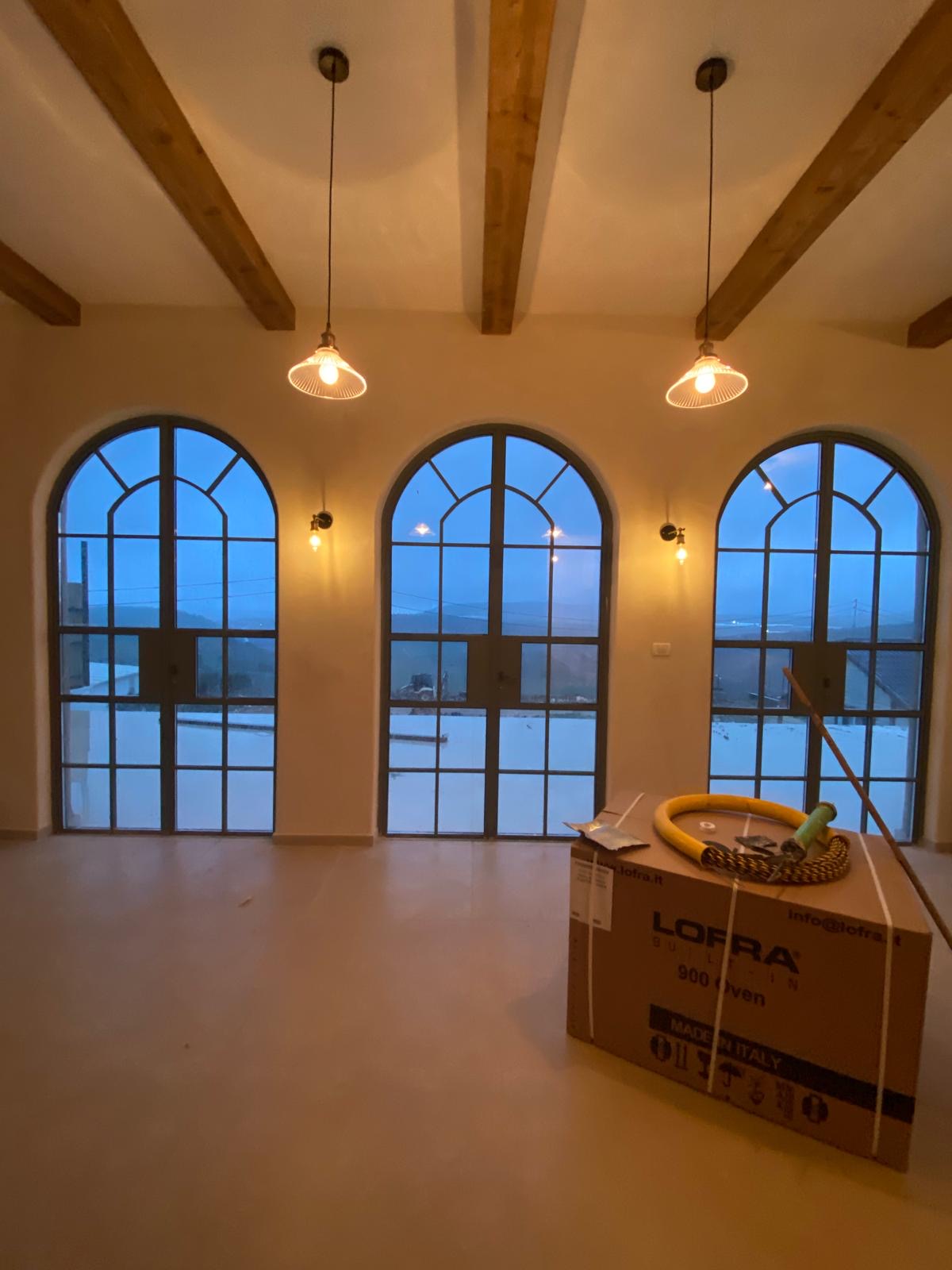 Three arched aluminum-frame windows in a living room